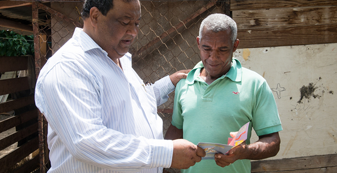 Photo of two men exchanging a card.